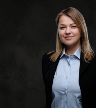 Portrait of a smiling blonde businesswoman formal dressed. Isolated on a dark textured background.